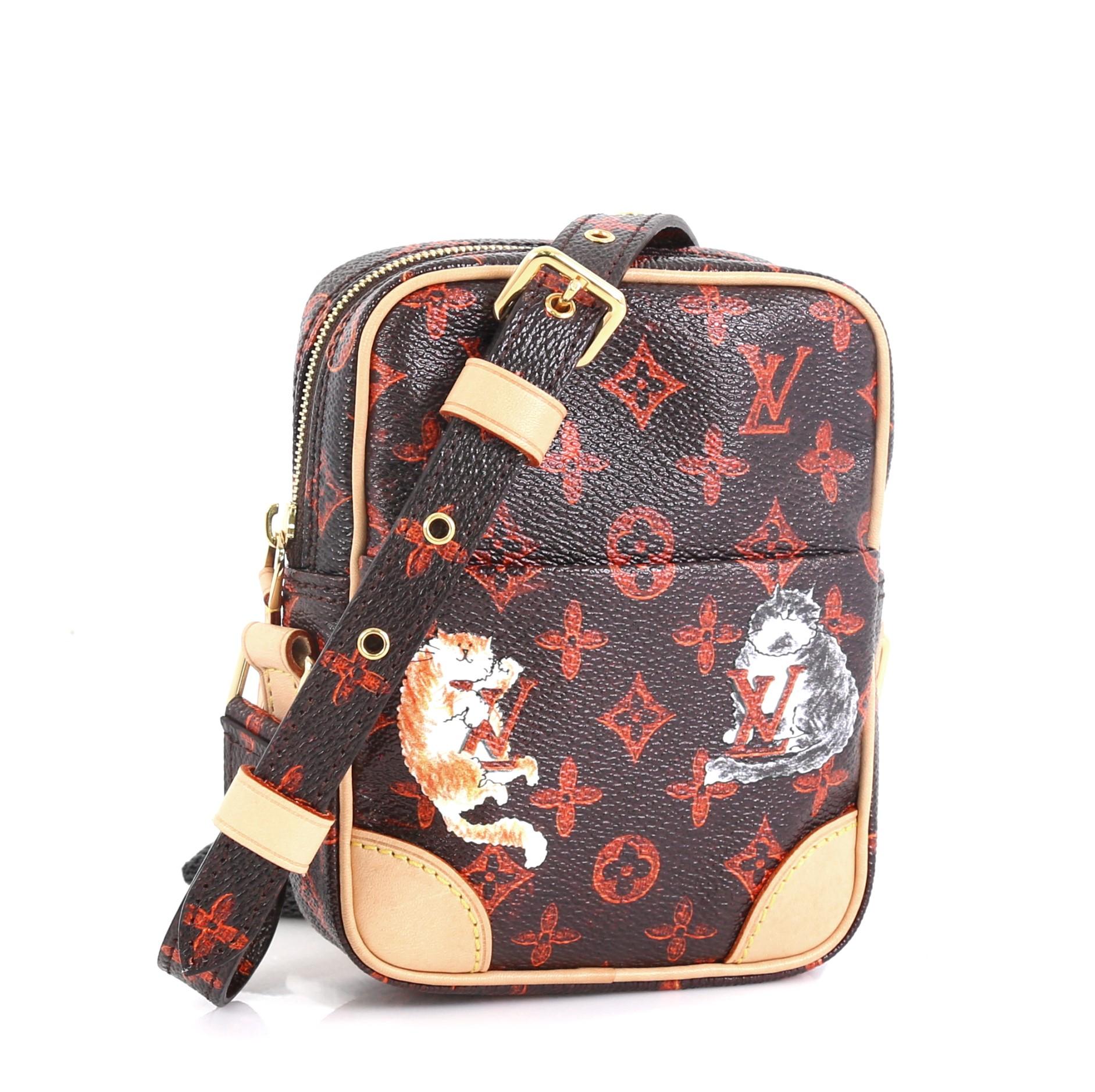 This Louis Vuitton Paname Bag Limited Edition Grace Coddington Catogram Canvas, crafted in orange and brown monogram coated canvas, features a crossbody strap, silk-screened playful cats and dogs, and gold-tone hardware. Its zip closure opens to an