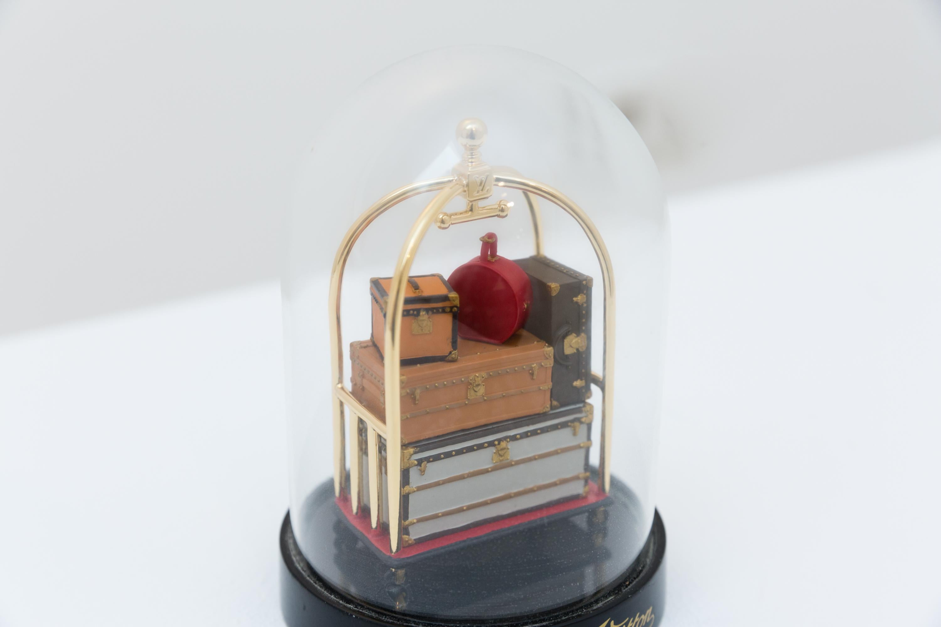 A Louis Vuitton desk paperweight showing a suitcase venture holding LV luggage inside.
The rare paperweights by Louis Vuitton are VIP gifts, made for special clients only and were not made for retail.