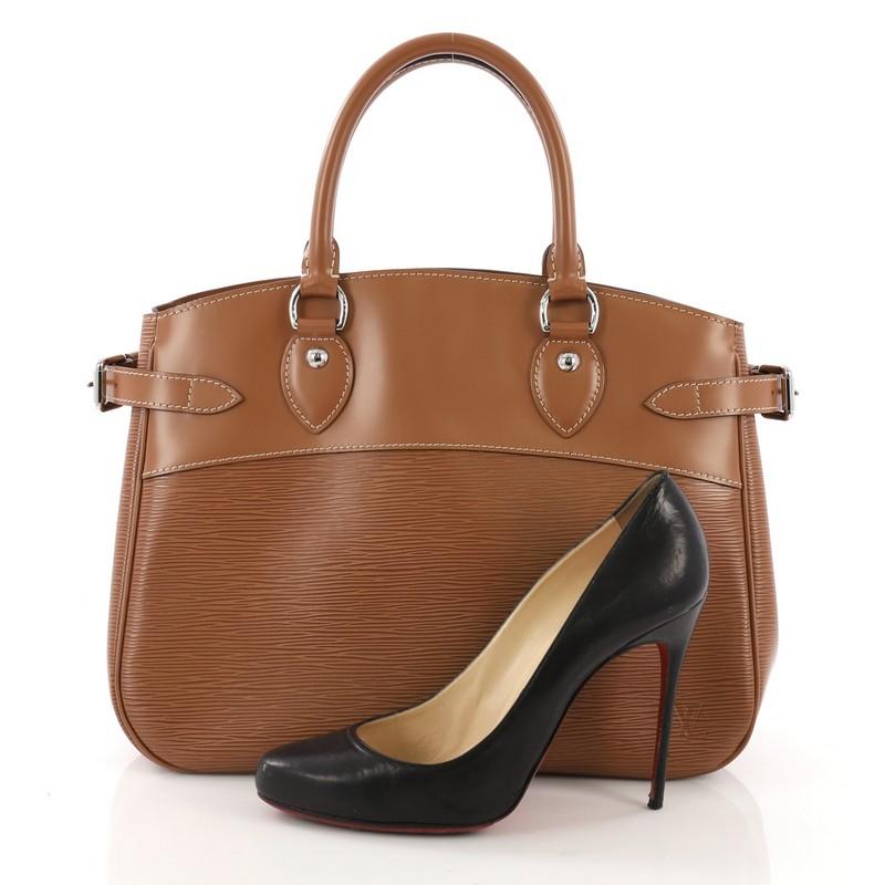 This Louis Vuitton Passy Handbag Epi Leather PM, crafted from brown epi leather, features dual rolled leather handles, side belt strap details, and silver-tone hardware. It opens to a brown fabric interior with middle zip compartment and side slip