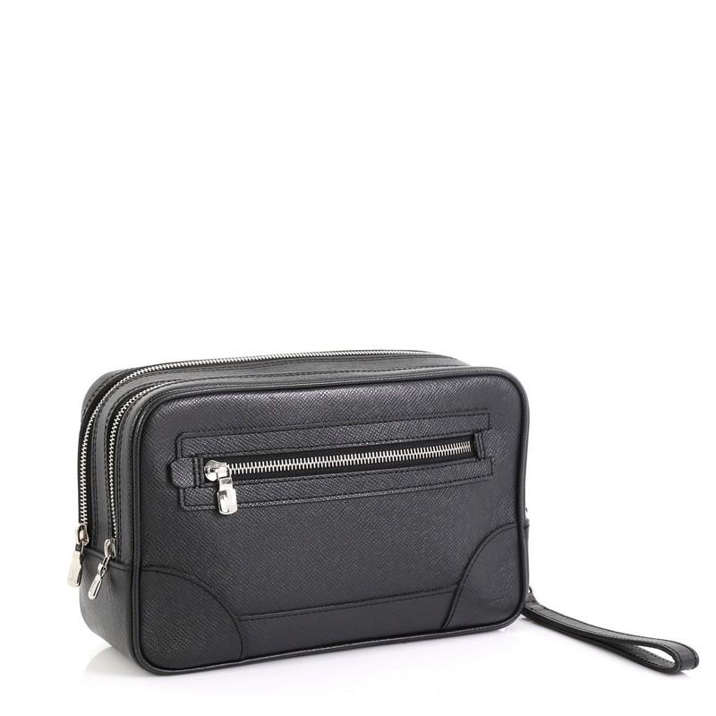 This Louis Vuitton Pavel Handbag Taiga Leather, crafted in black taiga leather, features a detachable wristlet strap, exterior zip pocket, subtle LV logo and silver-tone hardware. Its double zip closures open to a black fabric interior. Authenticity