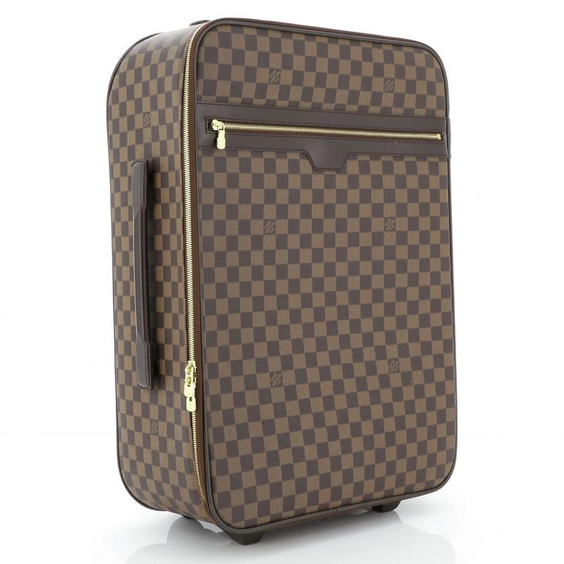 This Louis Vuitton Pegase Luggage Damier 55, crafted from damier ebene coated canvas. featuries leather trim, retractable handle with lock button and a silent rolling system, front zip pocket, and gold-tone hardware. Its zip closure opens to a brown