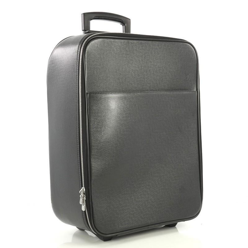 This Louis Vuitton Pegase Luggage Taiga Leather 45, crafted from black taiga leather, features a rolling system and silver-tone hardware. Its all-around zip closure opens to a black fabric interior with zip pockets and clothing protection flaps.