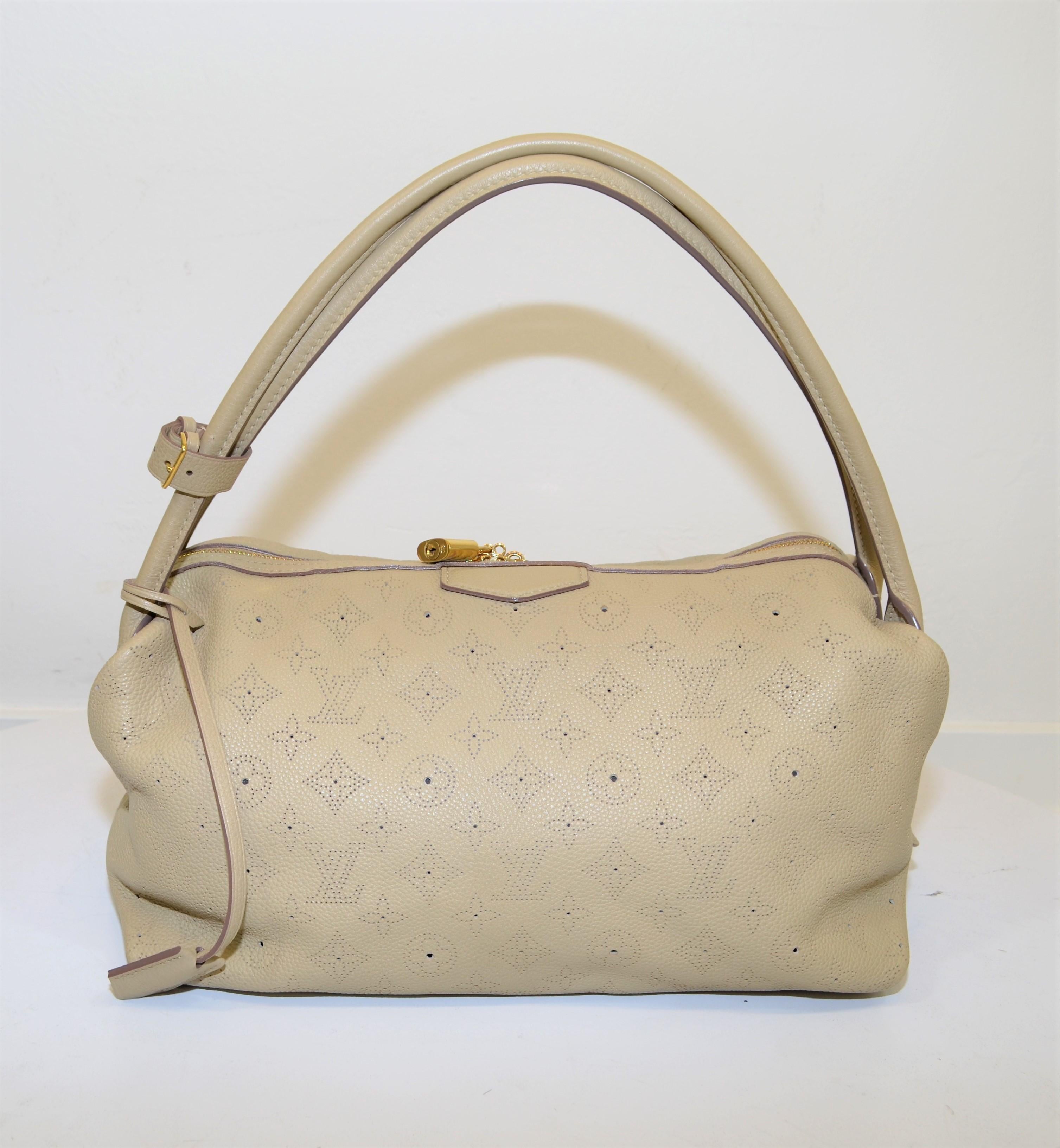 Louis Vuitton shoulder bag is featured in a neutral putty color perforated 