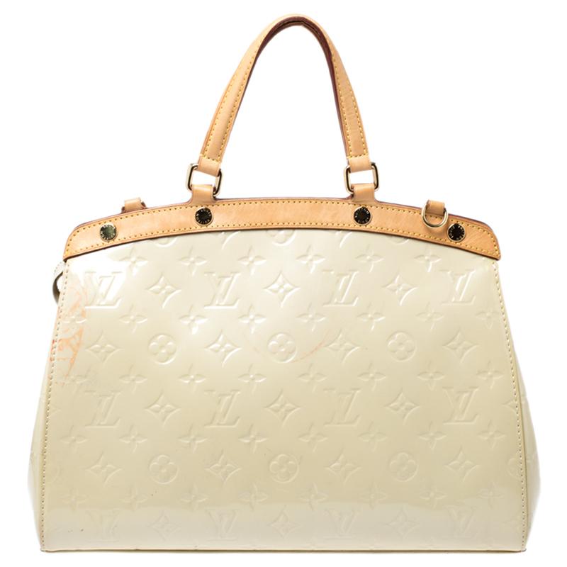 The feminine shape of Louis Vuitton's Brea is inspired by the doctor's bag. Crafted from Monogram Vernis in white, the bag has a perfect finish. The fabric interior is spacious and it is secured by a zipper. The bag features double handles,