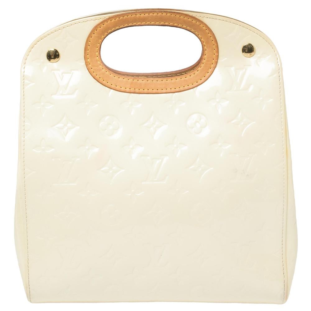 Louis Vuitton's Maple Drive bag has a clutch-like design. It is compact, classic, and luxurious. This here is crafted in Monogram Vernis and its interior is lined with fabric. The top has cut-out details to act as the handles.

