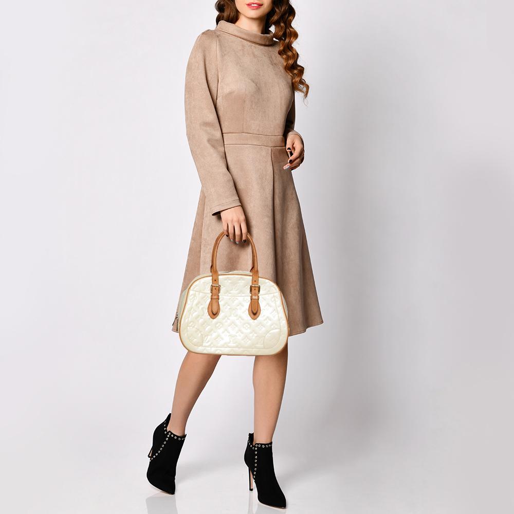 Elegant and polished, this bag takes you through your day with ease. Crafted in a smart silhouette from Monogram Vernis leather, it comes in a stunning shade of cream. The bag features dual-rolled handles and exterior slip pockets. The bag is