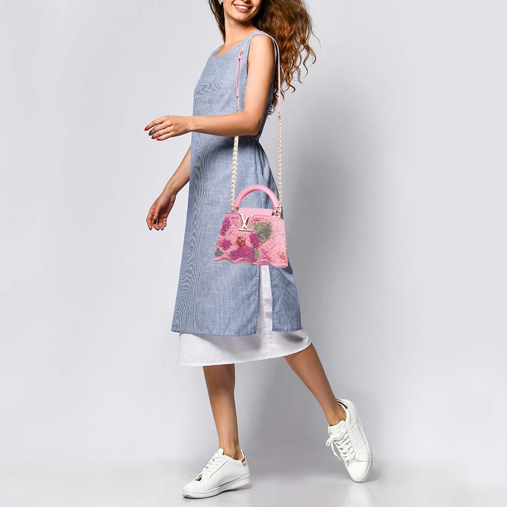 The Louis Vuitton bag from the Capushell collection radiates charm with its exquisite pink satin exterior and intricate embroidery. This Capucines mini bag features the iconic LV monogram and a delicate design combining luxury and playful