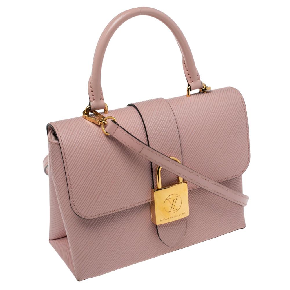 Die kleine, strukturierte Locky BB Tasche aus Epi-Leder kombiniert Raffinesse mit einem kühnen Statement-Stil, dank eines übergroßen LV-Vorhängeschlosses aus Goldmetall. Als modisches Accessoire für den Tag und den Abend kann sie je nach Stimmung