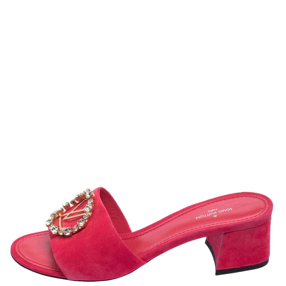 Louis Vuitton's Madeleine sandals exude a refined style and sophisticated vibe with their exquisite design. Crafted from pink-hued suede, they feature the LV logo on the front encircled by sparkling crystals and open toes. These beauties are