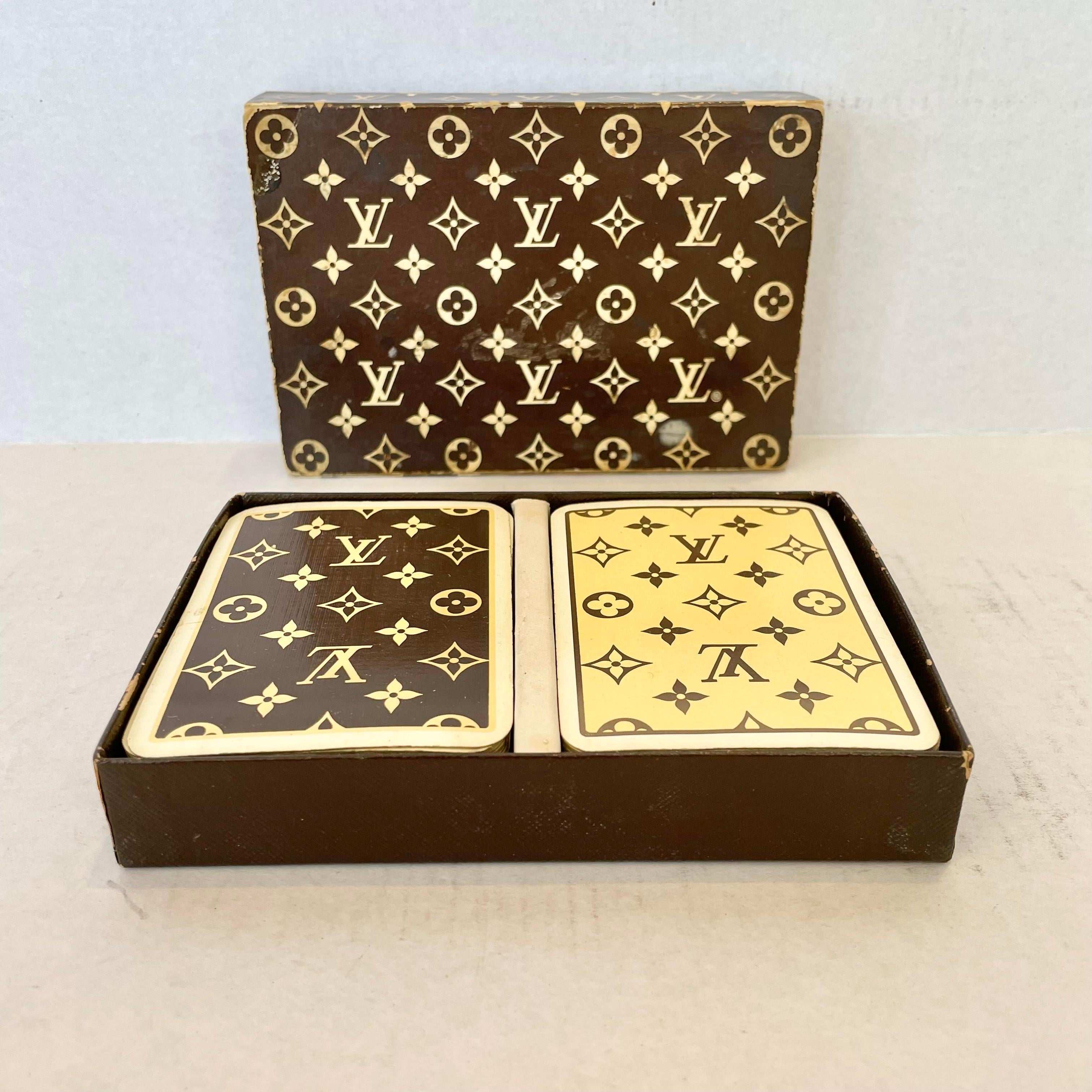 Vintage Louis Vuitton playing cards in the original box. Made in France, circa 1970s. There is a brown deck and a tan deck each with the iconic LV monogram design on the backs of the cards. Box is also printed with the LV monogram design. These