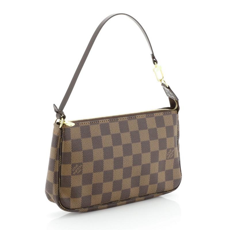 This Louis Vuitton Pochette Accessoires Damier, crafted from damier ebene coated canvas, features a flat leather strap and gold-tone hardware. Its zip closure opens to a red fabric interior. Authenticity code reads: CA2077 . 

Estimated Retail
