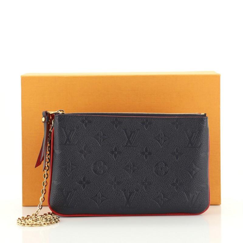 This Louis Vuitton Pochette Double Zip Monogram Empreinte Leather, crafted from blue leather, features a chain-link strap and gold-tone hardware. Its two-compartment zip closures opens to a red microfiber interior with multiple card slots.