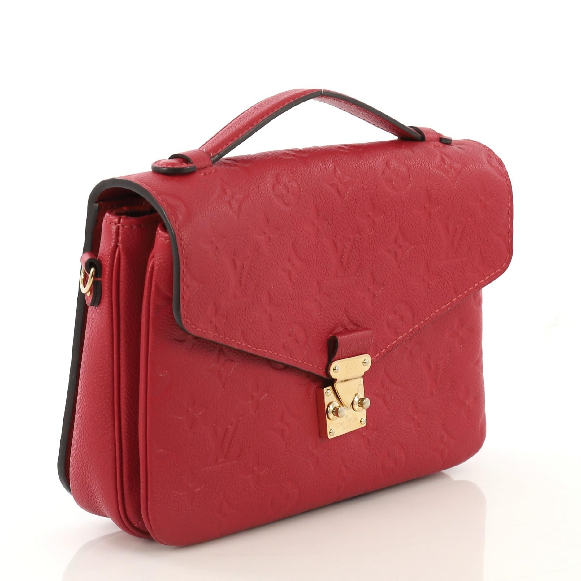 This Louis Vuitton Pochette Metis Monogram Empreinte Leather, crafted in red monogram empreinte leather, features a leather top handle, exterior back zip pocket, and gold-tone hardware. Its S-lock closure opens to a red fabric interior with two open