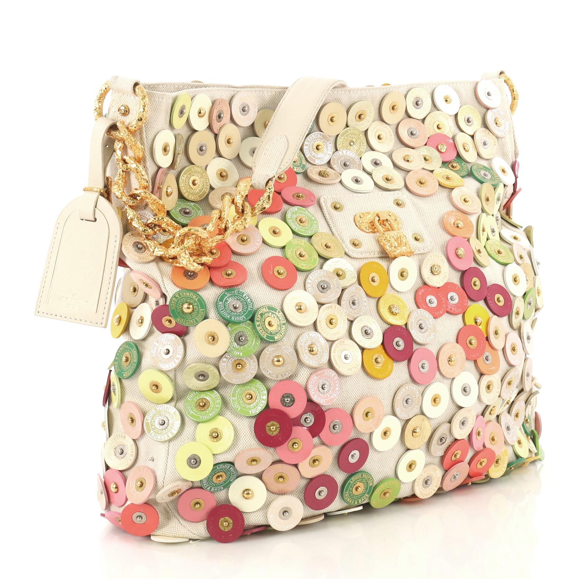 This Louis Vuitton Polka Dot Fleur Morgane Handbag Embellished Canvas, crafted in white multicolor embellished canvas, features chain link strap and gold-tone hardware. Its magnetic snap closure opens to a tan fabric interior with zip pocket.