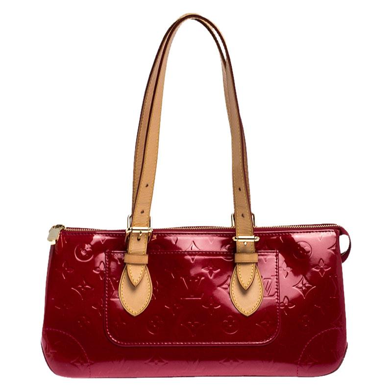 The Rosewood Avenue bag from Louis Vuitton is fashioned in Monogram Vernis with tan leather handles. This sleek, rectangular style is secured with a top zip closure and features an exterior wall pocket. It opens to a fabric-lined interior that can