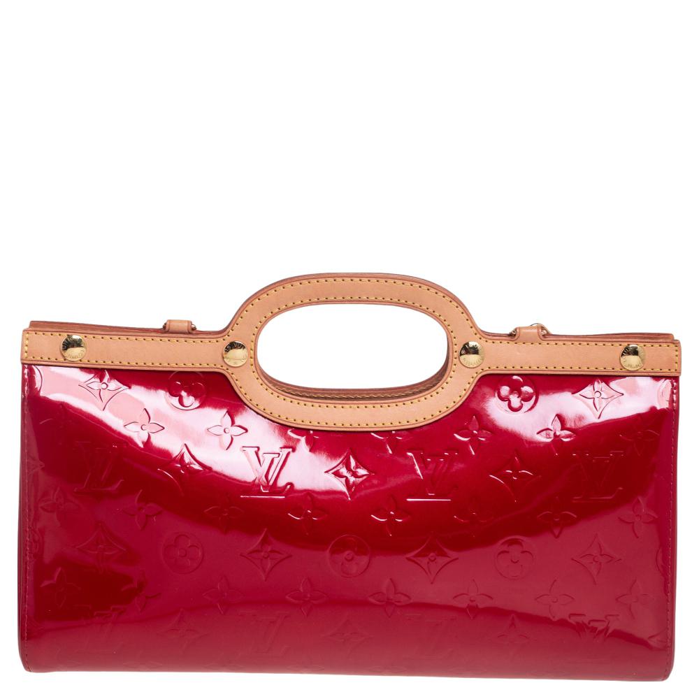 This Roxbury Drive bag from Louis Vuitton is sure to make heads turn. The monogram pattern is embossed on the patent leather body that gives it a polished look. The red-colored exterior features smooth trims, a removable shoulder strap, and