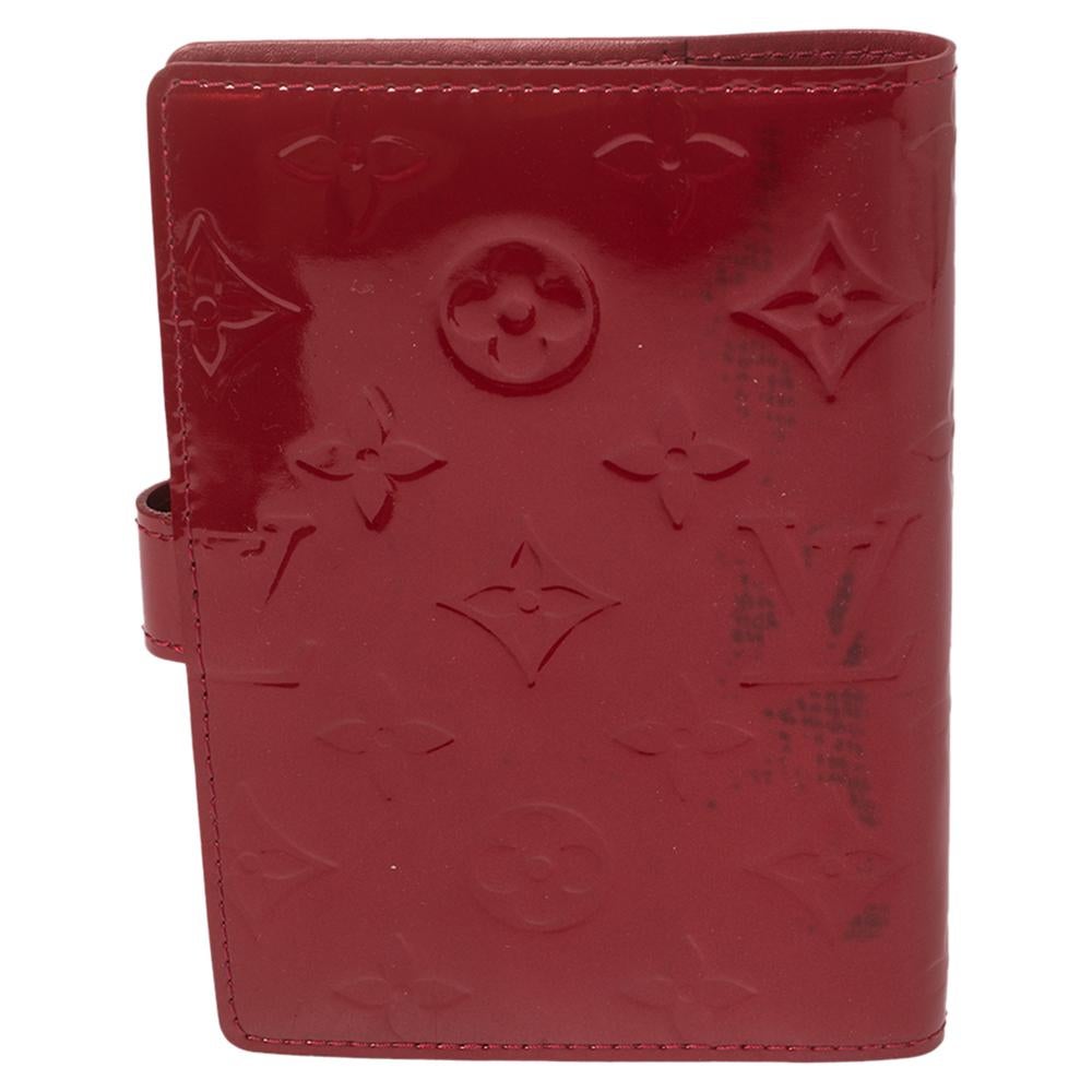 This compact and functional Louis Vuitton agenda cover in monogram Vernis can be used as an address book, calendar, or notepad. It features multiple credit card slots and a press stud closure. The LV agenda cover is accompanied by a matching zip