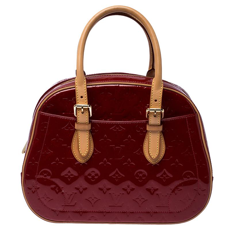 Elegant and polished, this bag takes you through your day with ease. Crafted from Monogram Vernis patent leather, it features dual rolled handles and exterior slip pockets. The bag is secured by a wide two-way zip closure that opens to a roomy