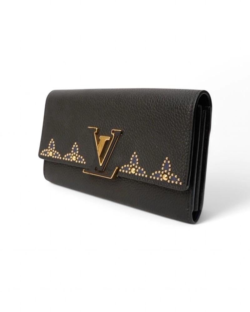 Portafoglio firmato Louis Vuitton, modello Capucines Taurillon, realizzato in pelle granulata nera con hardware dorato. Dotato di una patta  impreziosita dal classico logo del brand “LV” in metallo e pelle, con chiusura a clip. Internamente