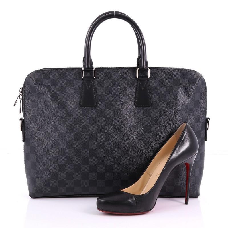 This Louis Vuitton Porte-Documents Jour Bag Damier Graphite, crafted in black damier graphite coated canvas, features dual rolled leather handles and silver-tone hardware. Its two-way zip closure opens to a black fabric interior with multiple slip