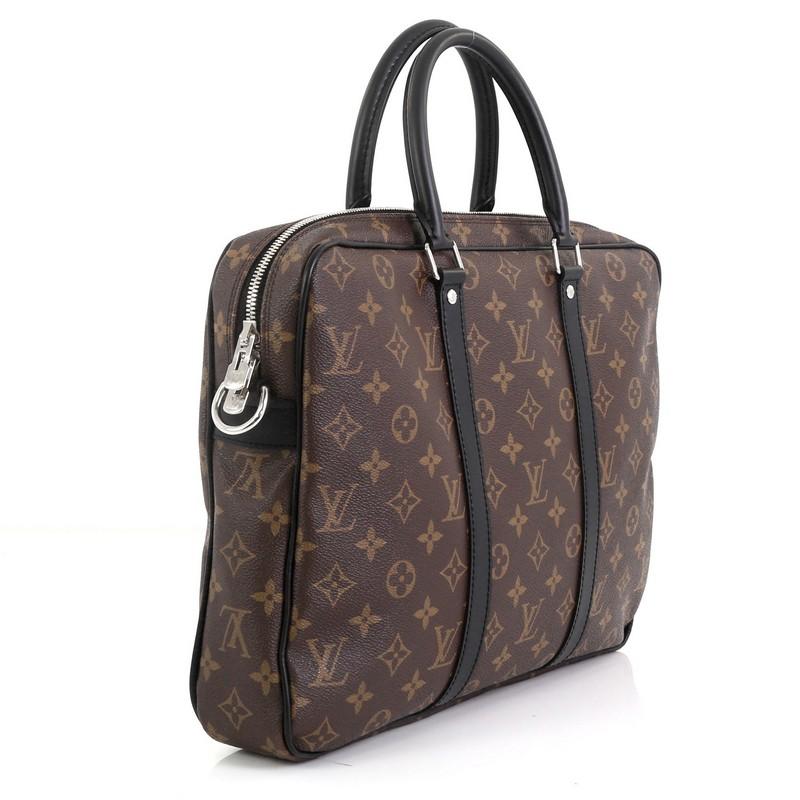 This Louis Vuitton Porte-Documents Voyage Briefcase Macassar Monogram Canvas PM, crafted from brown monogram coated canvas, features dual rolled handles, leather trim, and silver-tone hardware. Its zip closure opens to a red fabric interior.