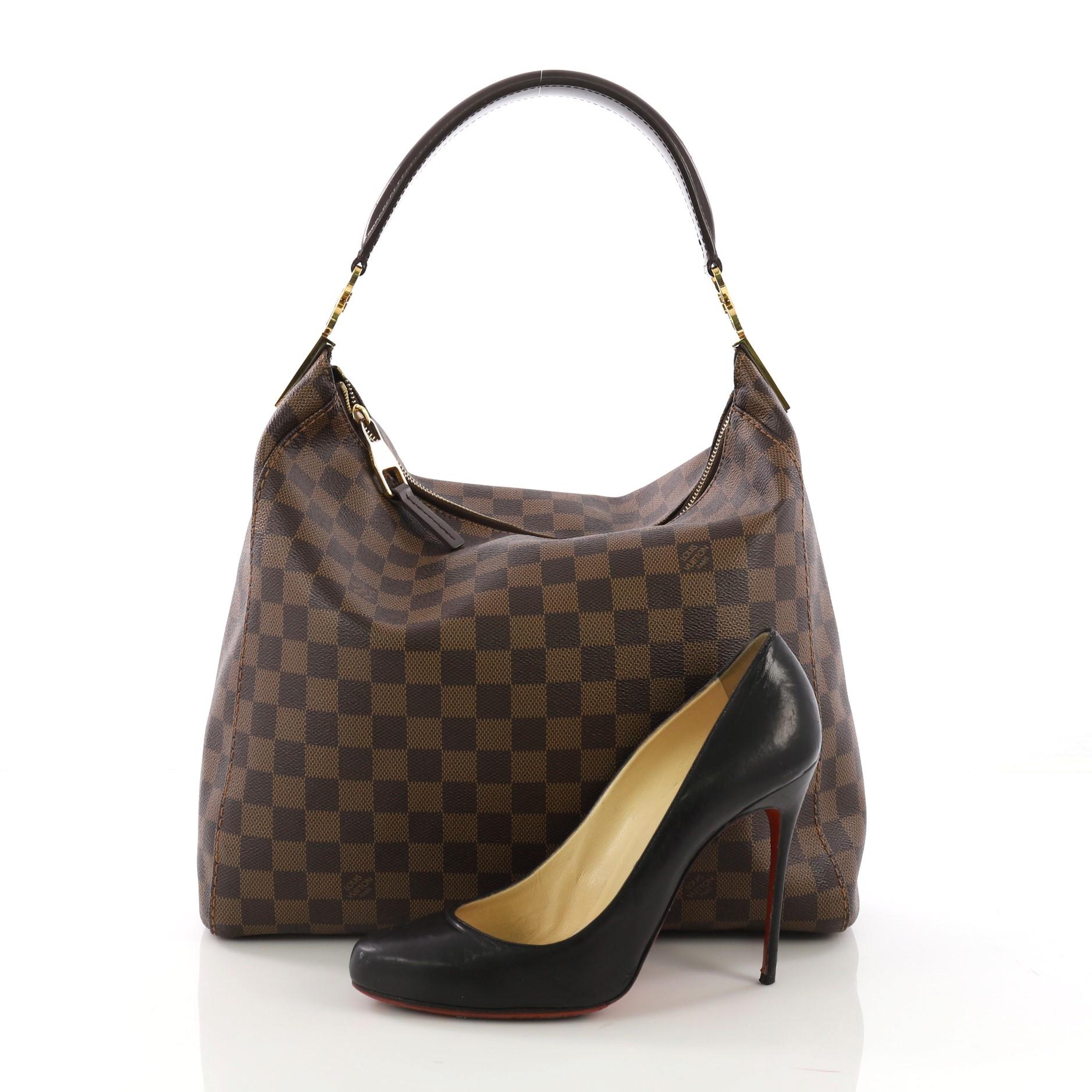 This Louis Vuitton Portobello Handbag Damier PM, crafted in damier ebene coated canvas, features a single looped leather handle and gold-tone hardware. Its top zip closure opens to a brown microfiber interior with side zip and slip pockets.
