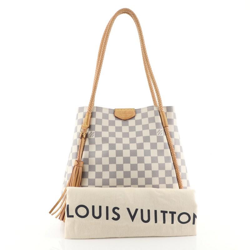 This Louis Vuitton Propriano Handbag Damier, crafted from damier azur coated canvas, features braided vachetta leather shoulder straps, tassel charm, and gold-tone hardware. Its magnetic snap closure opens to a pink microfiber interior with zip