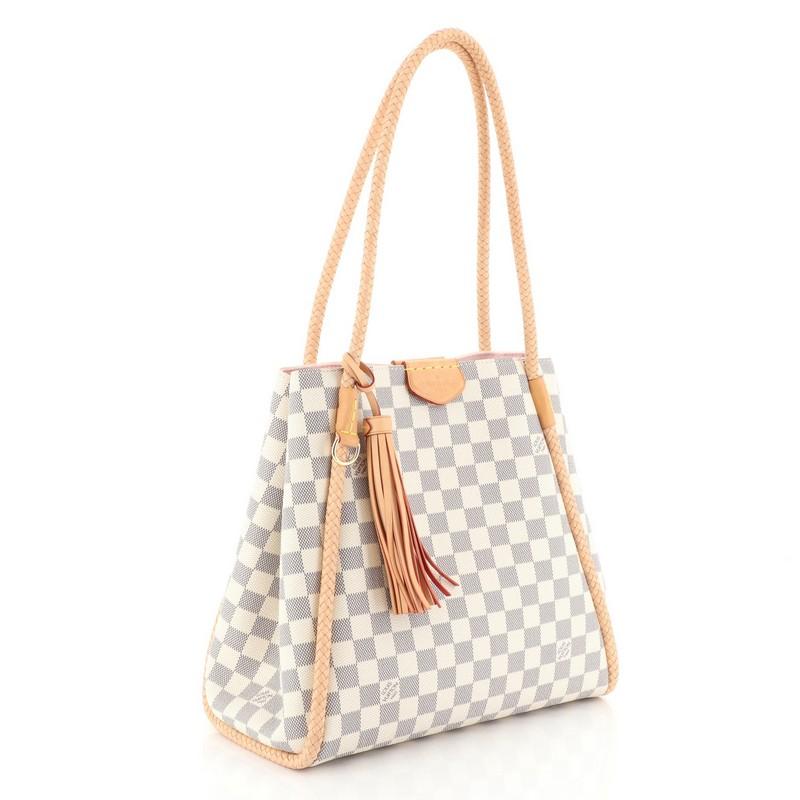 This Louis Vuitton Propriano Handbag Damier, crafted from damier azur coated canvas, features braided vachetta leather shoulder straps, tassel charm, and gold-tone hardware. Its magnetic snap closure opens to a pink microfiber interior with zip