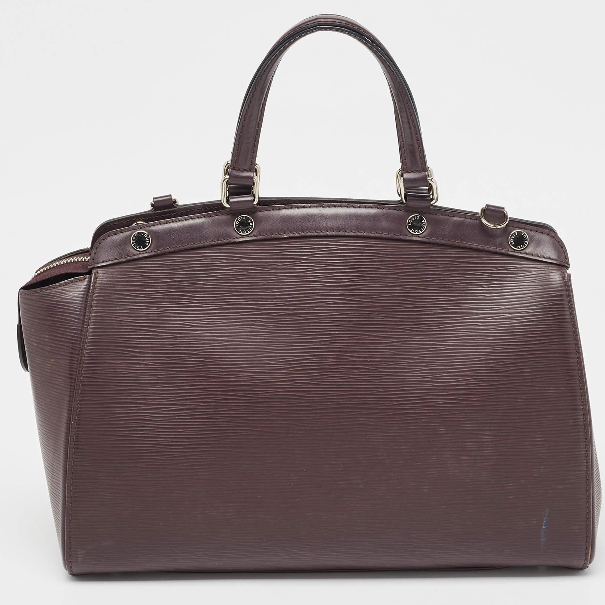 The feminine shape of Louis Vuitton's Brea is inspired by the doctor's bag. Crafted from Epi leather in a lovely shade of brown, the bag has a perfect finish. The fabric interior is spacious and it is secured by a zipper. The bag features double