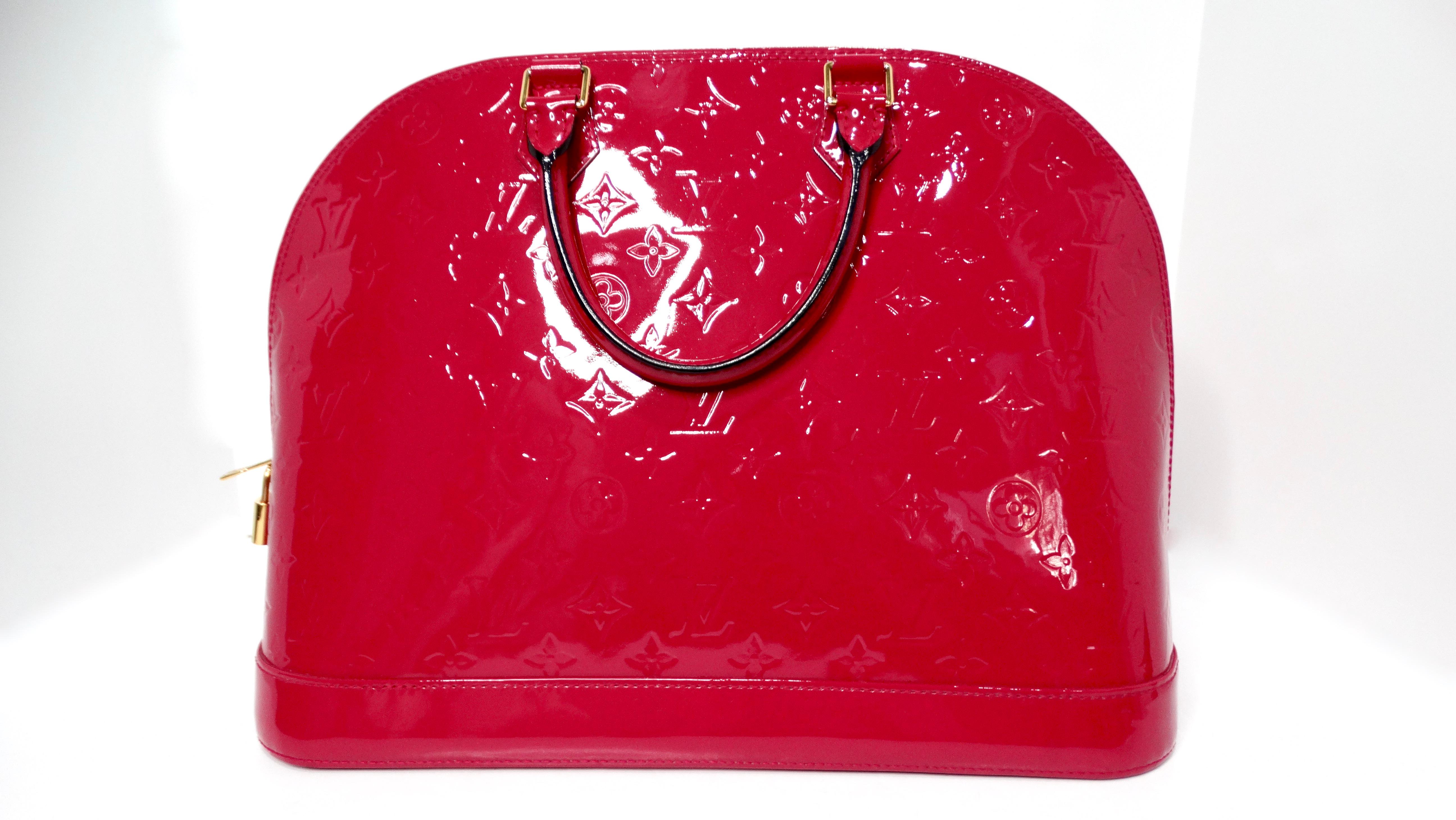 The Louis Vuitton Raspberry Alma in Monogram Vernis Patent Leather is a true statement piece, exuding sophistication and vibrant style. Crafted from luxurious patent leather embossed with the iconic Louis Vuitton monogram, its rich raspberry hue is