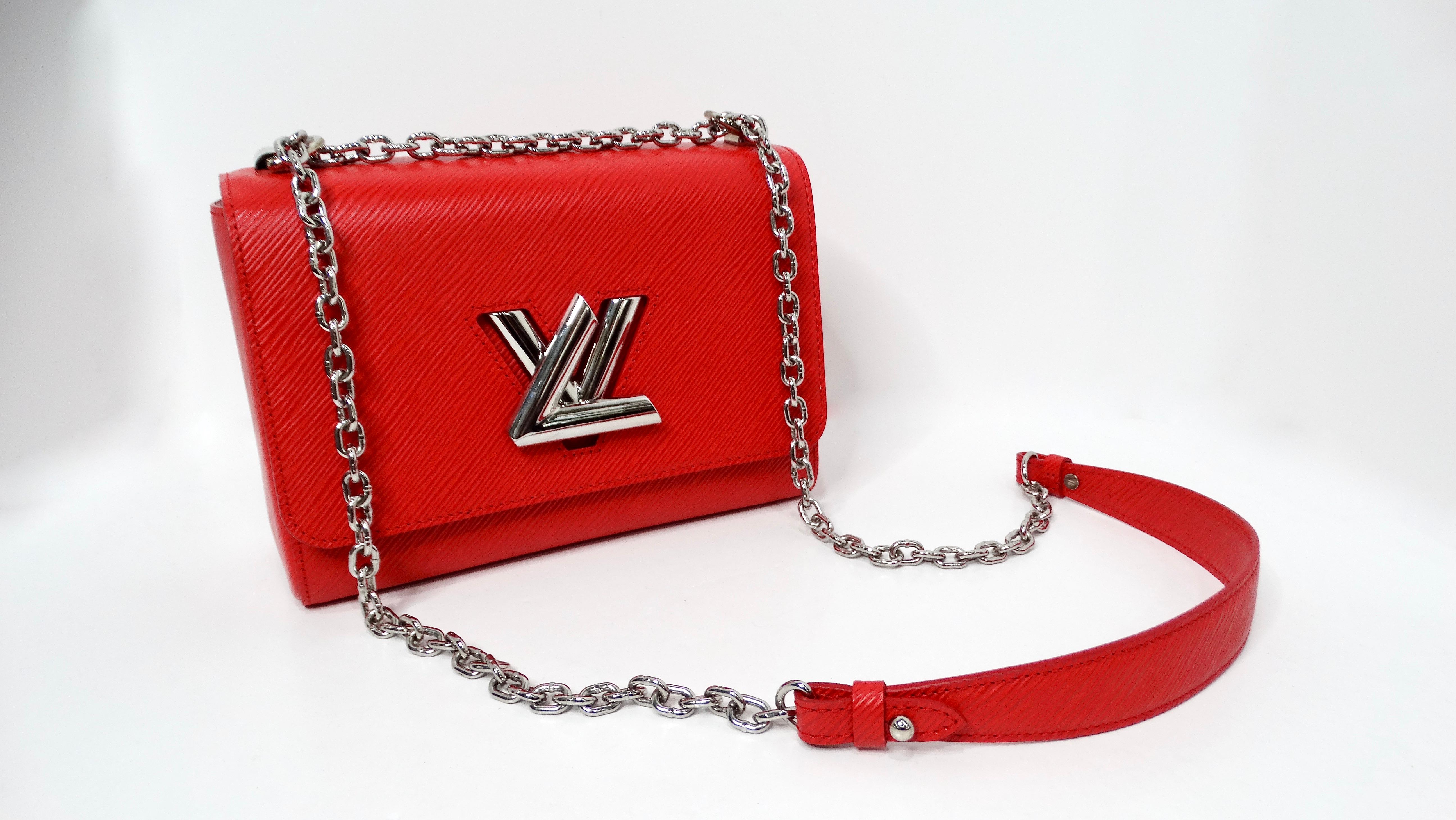 The Louis Vuitton Red Epi Twist Shoulder Bag with Silver-Tone Hardware is a striking and sophisticated accessory that exudes modern elegance. Crafted from the iconic Epi leather, known for its textured and durable finish, this bag in a vibrant red