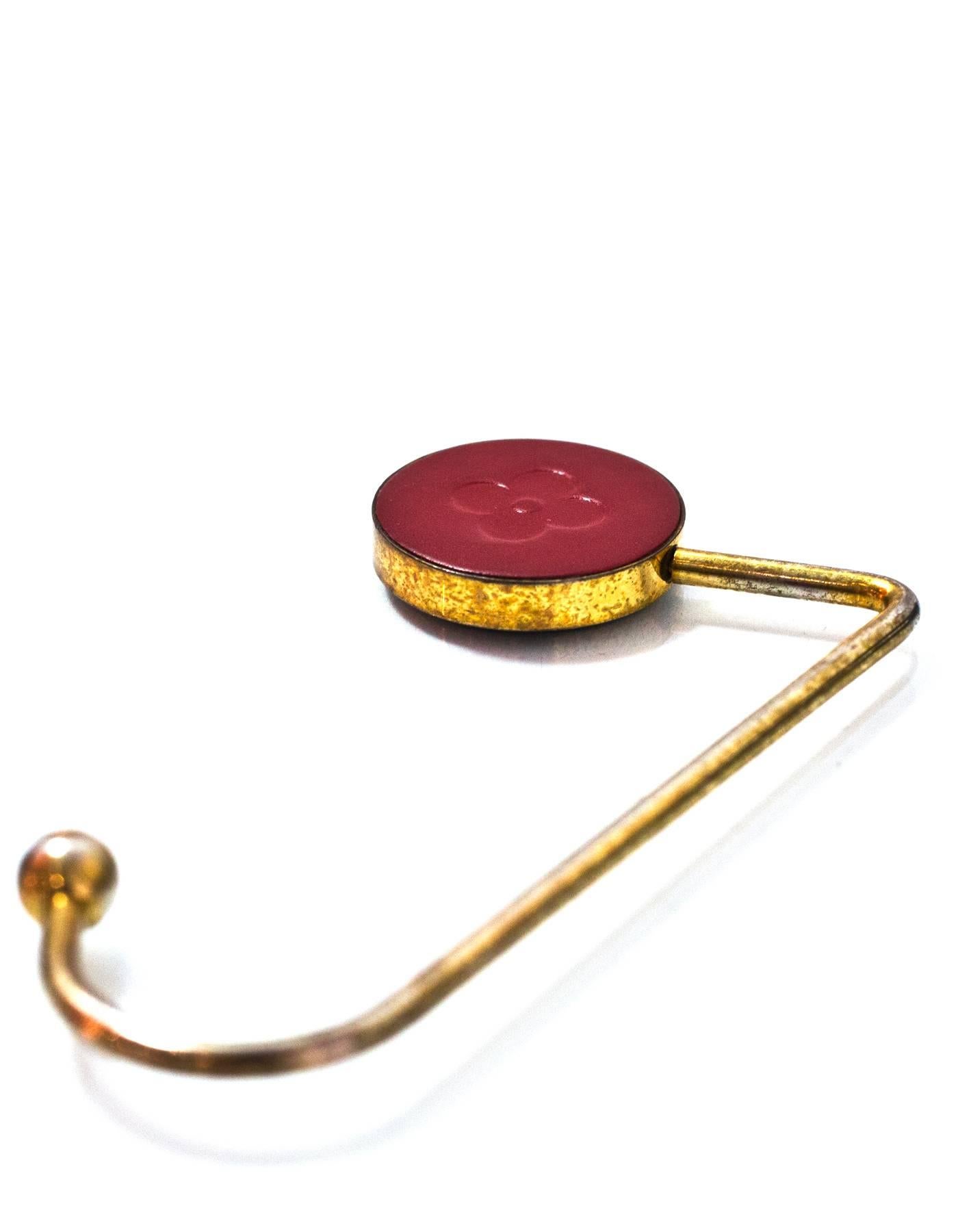 Louis Vuitton Red Leather & Goldtone Purse Hook
This was a VIP gift, not sold in stores

Color: Red, gold
Hardware: Goldtone
Materials: Leather and metal
Overall Condition: Very good pre-owned condition with the exception of tarnishing and surface