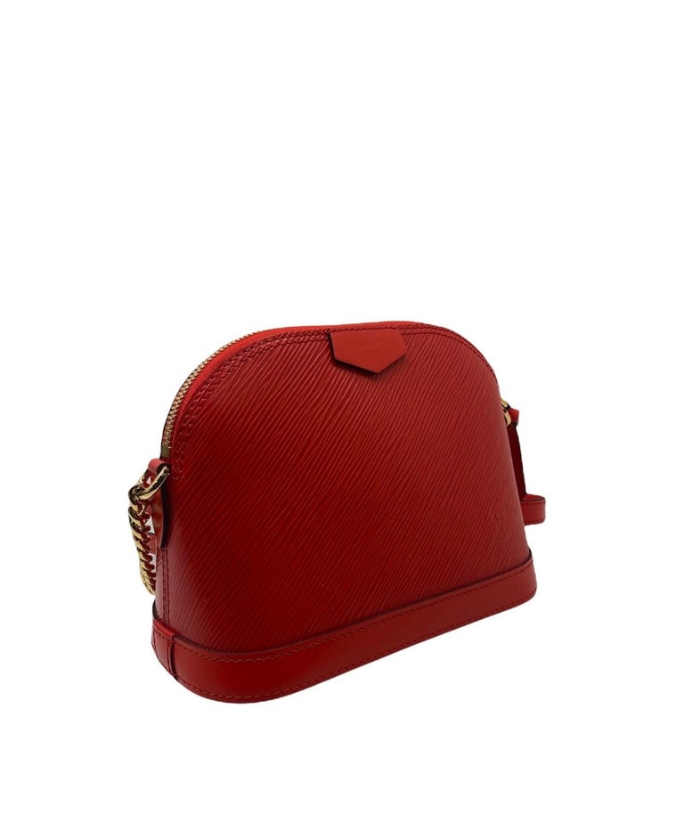 Louis Vuitton Alma BB shoulder bag in red epi leather with gold hardware.  It has a zip closure. The interior is lined with a red suede and is equipped with an internal pocket.  The bag is equipped with a chain shoulder strap with a layer of red