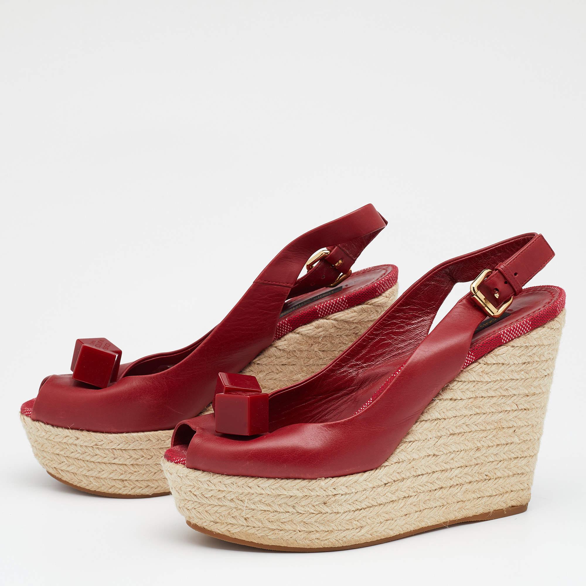 Complete your outfits with these Louis Vuitton wedge sandals. They are made from red leather and feature peep toes, cube-embellished uppers, buckle slingbacks, and espadrille wedge heels.

