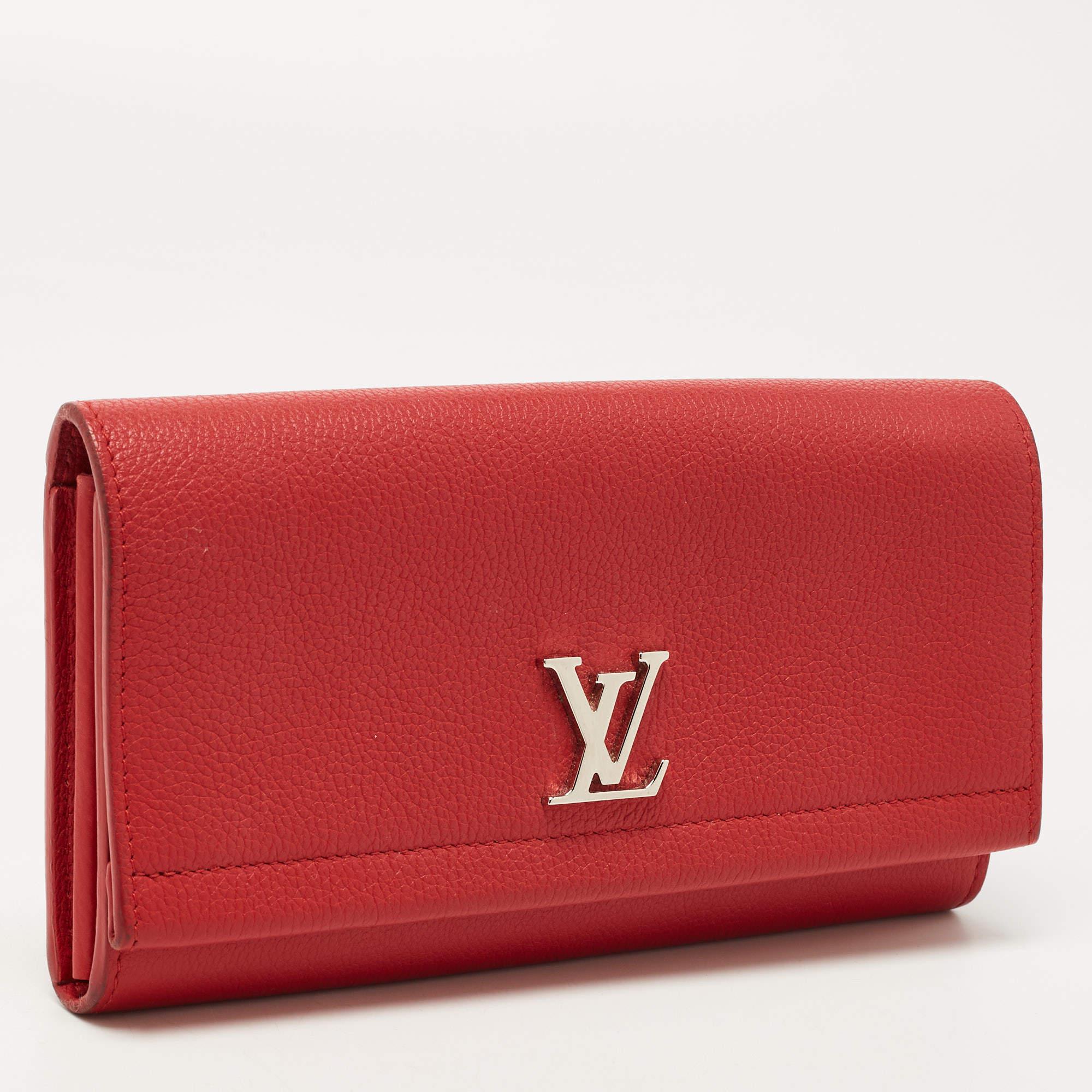 Dieses luxuriöse Lock Me ll Portemonnaie von Louis Vuitton ist eine wahre Freude für jeden, der es bei sich trägt. Die Klappe ist aus rotem Leder gefertigt und mit dem LV-Logo aus silberfarbenem Metall versehen. Sie lässt sich öffnen und gibt den