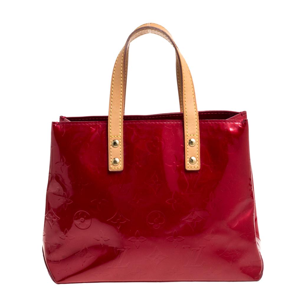 From the vast Louis Vuitton collection, the red-hued Reade PM tote will add a little glam that you've been missing! This bag is crafted from Monogram Vernis leather with leather handles. The open interior is lined with fabric and comes with one