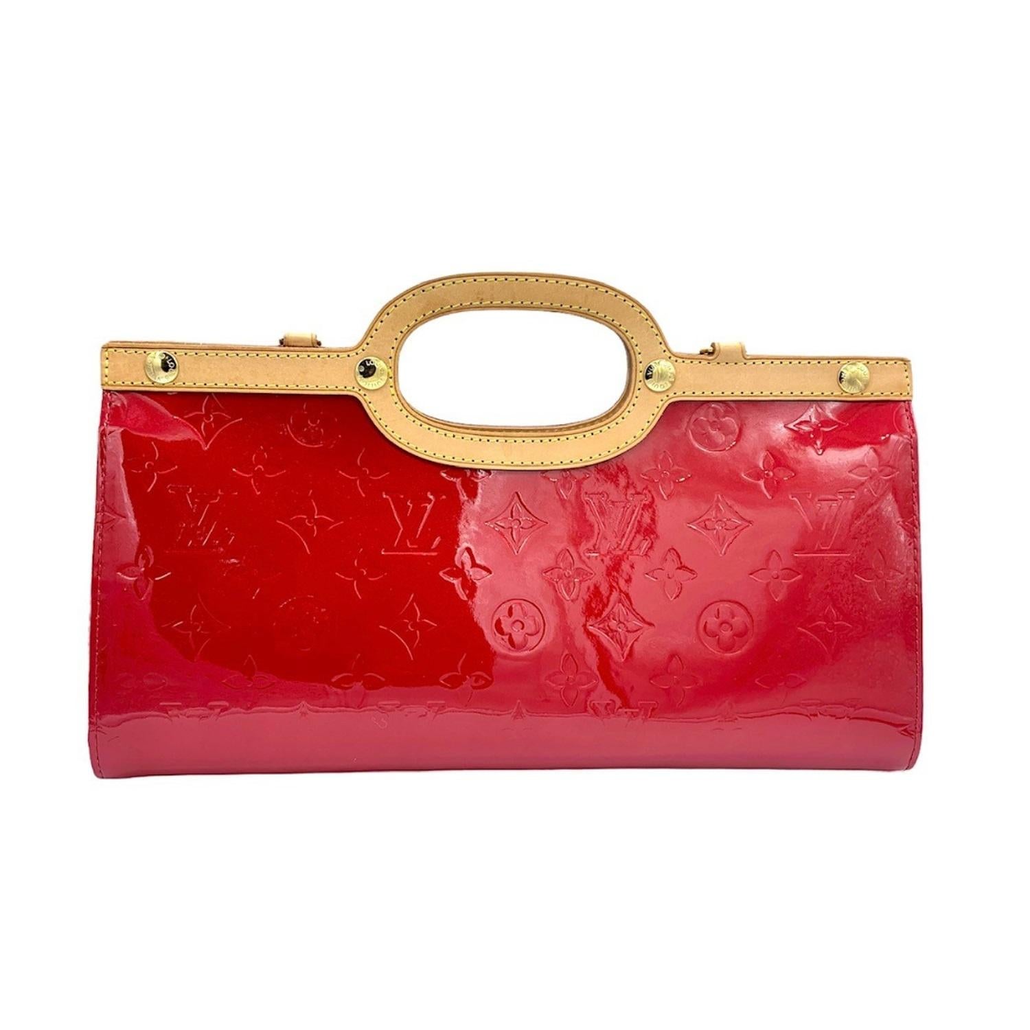 This chic handbag tote is crafted of Louis Vuitton monogram embossed vernis patent leather in the distinctive bright red color. The bag features a top crest of vachetta cowhide leather with cutaway top handles and brass hardware. The top unsnaps to