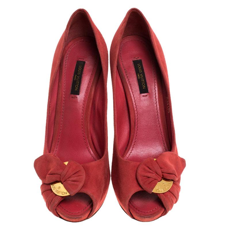 Issus de la collection printemps 2011 de Louis Vuitton, ces escarpins à bout ouvert 'Catania' sont réalisés en daim rouge et sont ornés d'un nœud froncé et de plaques LV gravées en métal doré. Ces beautés reposent sur des talons de 11 cm pour vous
