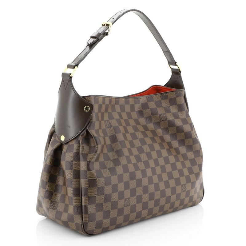 This Louis Vuitton Reggia Handbag Damier, crafted from damier ebene coated canvas, features an adjustable shoulder strap, chocolate brown leather trims and gold-tone hardware. Its magnetic snap closure opens to a red microfiber interior with zip and