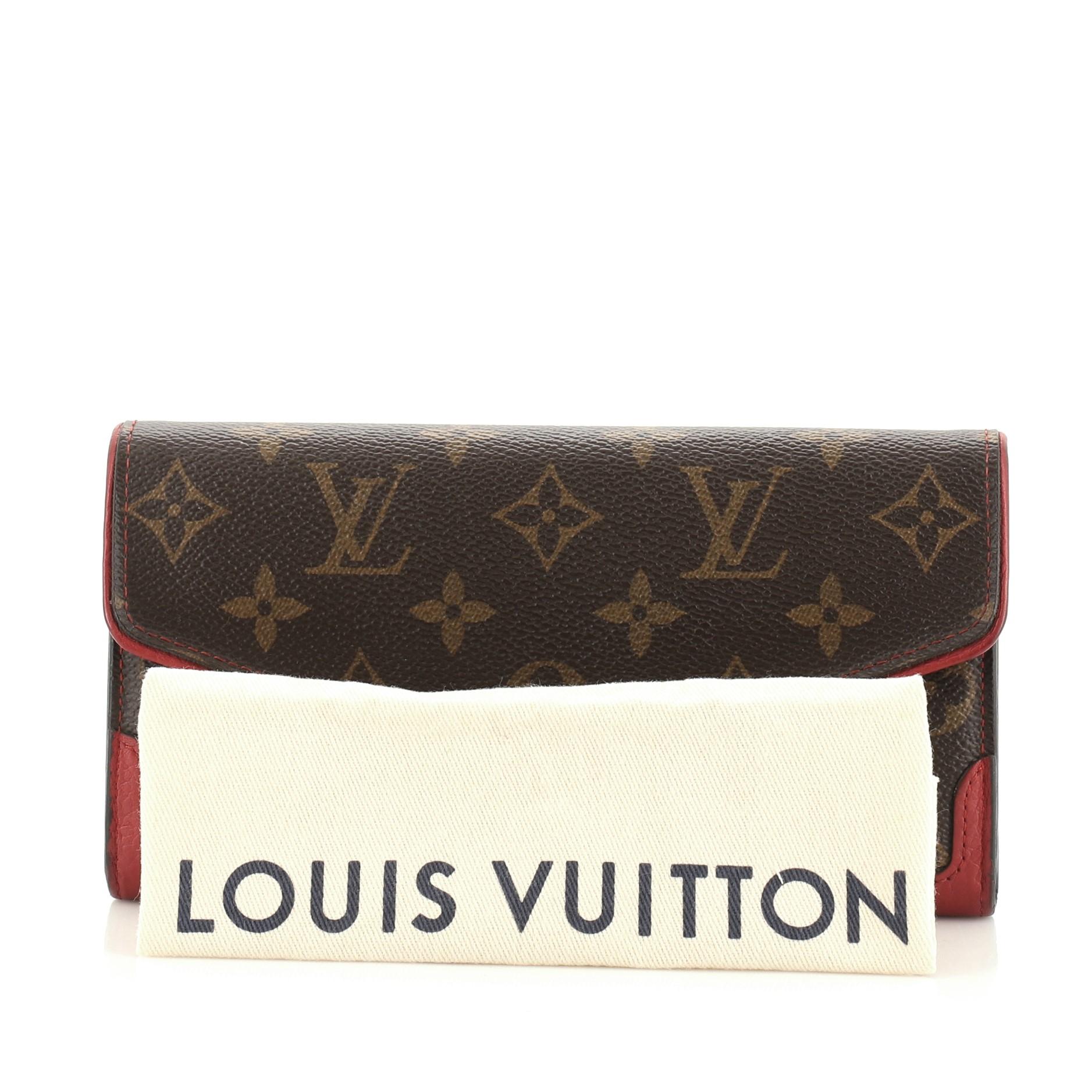 This Louis Vuitton Retiro Sarah Wallet Monogram Canvas, crafted from brown monogram coated canvas, features red leather trims and gold-tone hardware. Its snap button closure opens to a red leather and brown coated canvas interior with a center zip