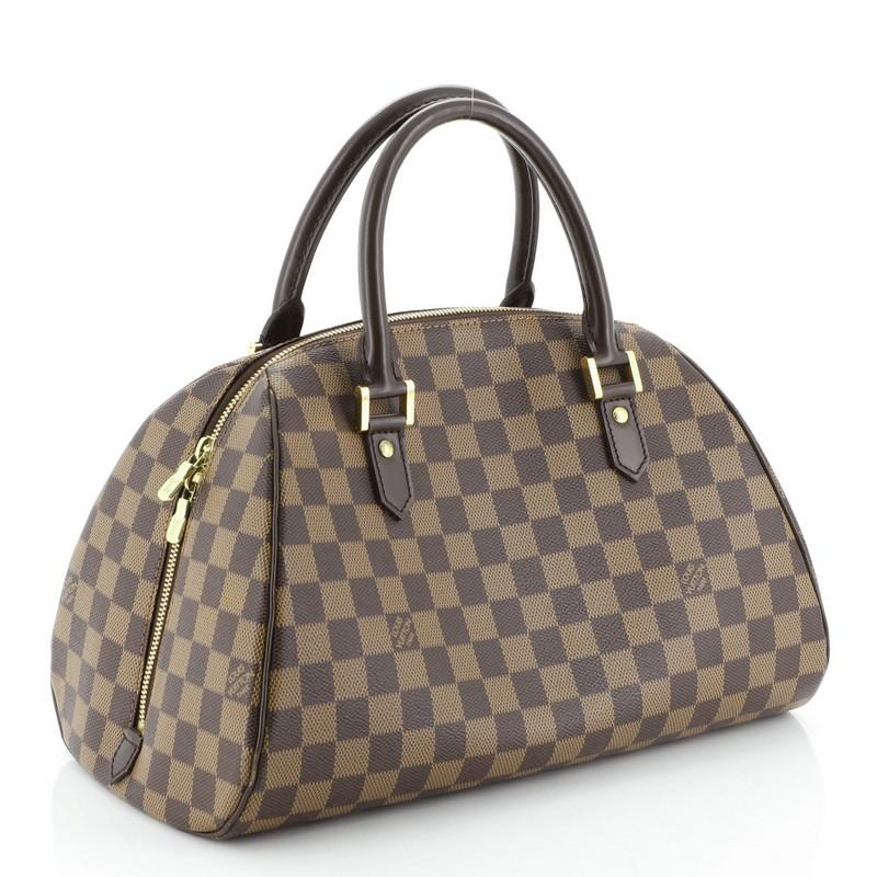 This Louis Vuitton Ribera Handbag Damier MM, crafted from damier ebene coated canvas, features dual rolled leather handles, leather trim, and gold-tone hardware. Its two-way zip closure opens to an orange fabric interior with slip pockets.