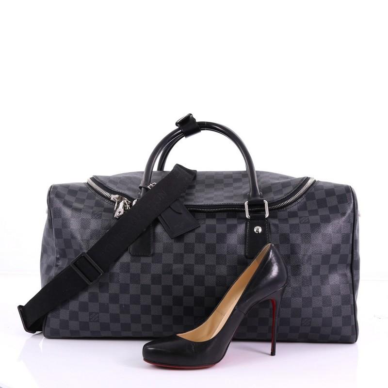 This Louis Vuitton Roadster Handbag Damier Graphite, crafted with damier graphite coated canvas, features dual rolled leather handles, protective base studs, and silver-tone hardware. Its zip-around closure opens to a black fabric interior with side
