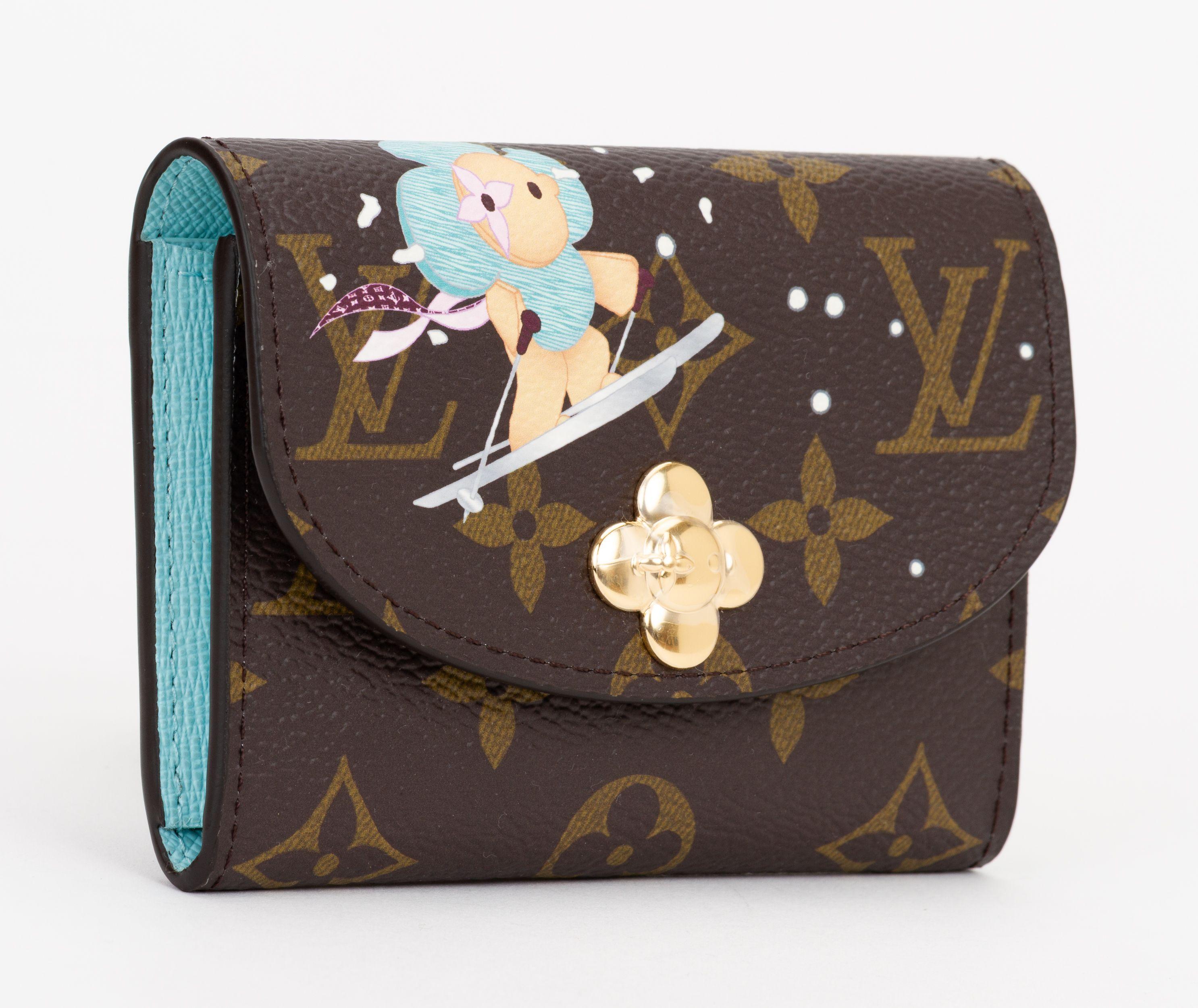 Louis Vuitton Rosalie Coin Purse is in monogram coated canvas, with ski illustration on front. Features leather trim, gold tone hardware, blue interior with a zipper pocket and card slots. New and comes with original box and dust cover.