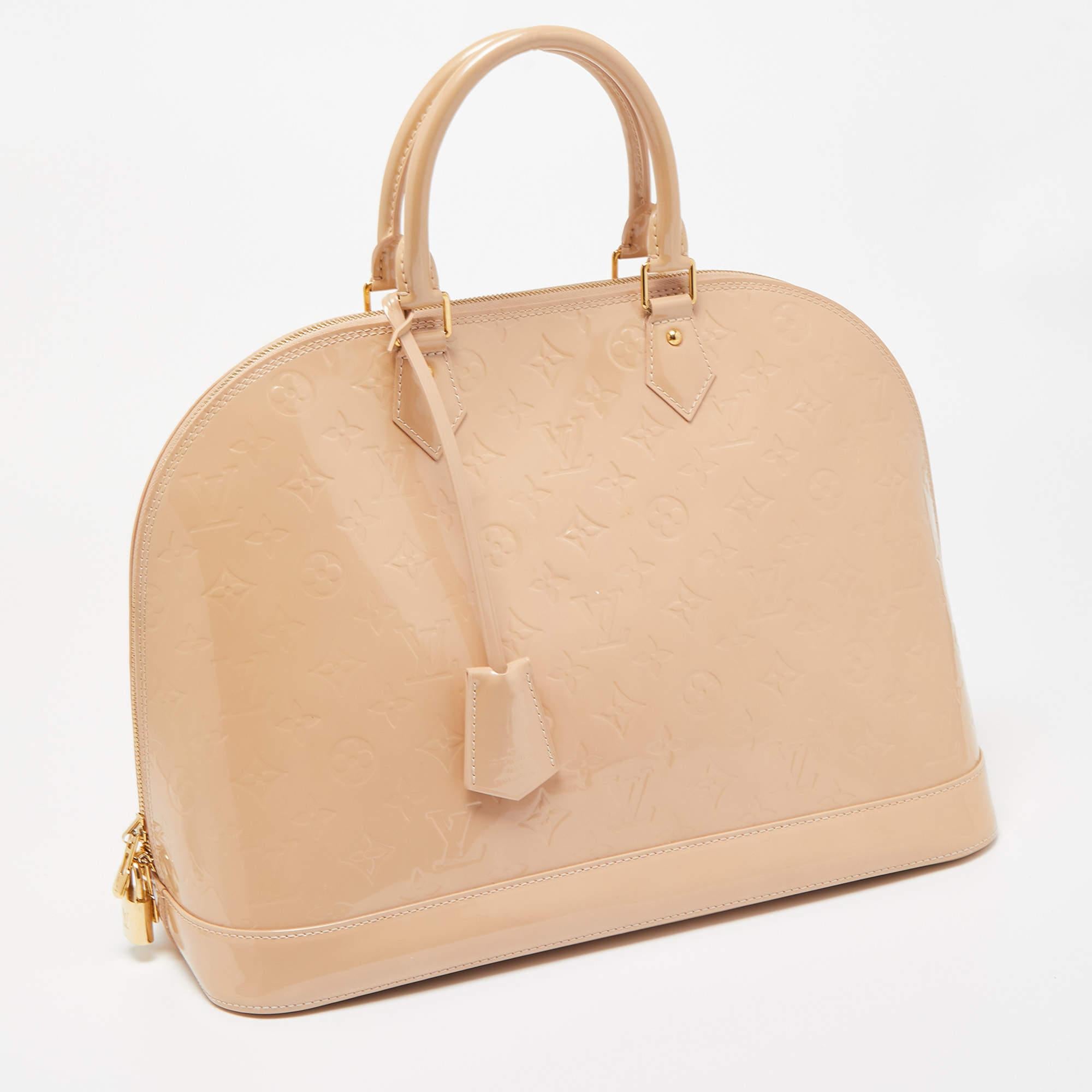 The Louis Vuitton Alma bag is an iconic fashion accessory. Crafted from glossy Monogram Vernis patent leather, it features the iconic Alma silhouette with dual top handles, a structured body, and gold-tone hardware. This elegant and timeless handbag