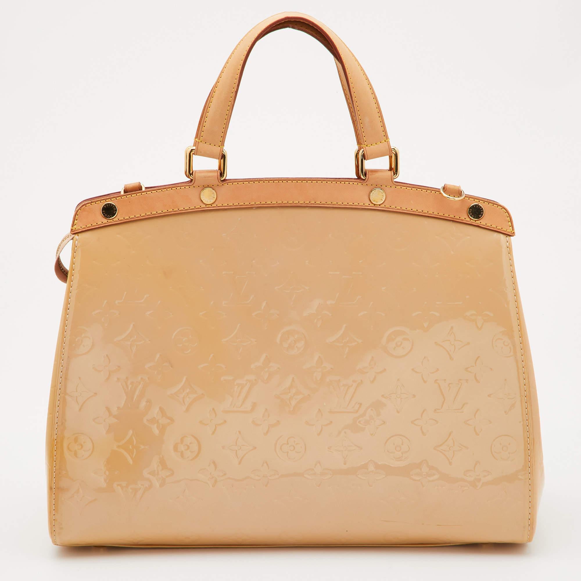 The feminine shape of Louis Vuitton's Brea is inspired by the doctor's bag. Crafted from Monogram Vernis, the bag has a fine finish. The fabric interior is spacious and it is secured by a zipper. The bag features double handles, protective metal