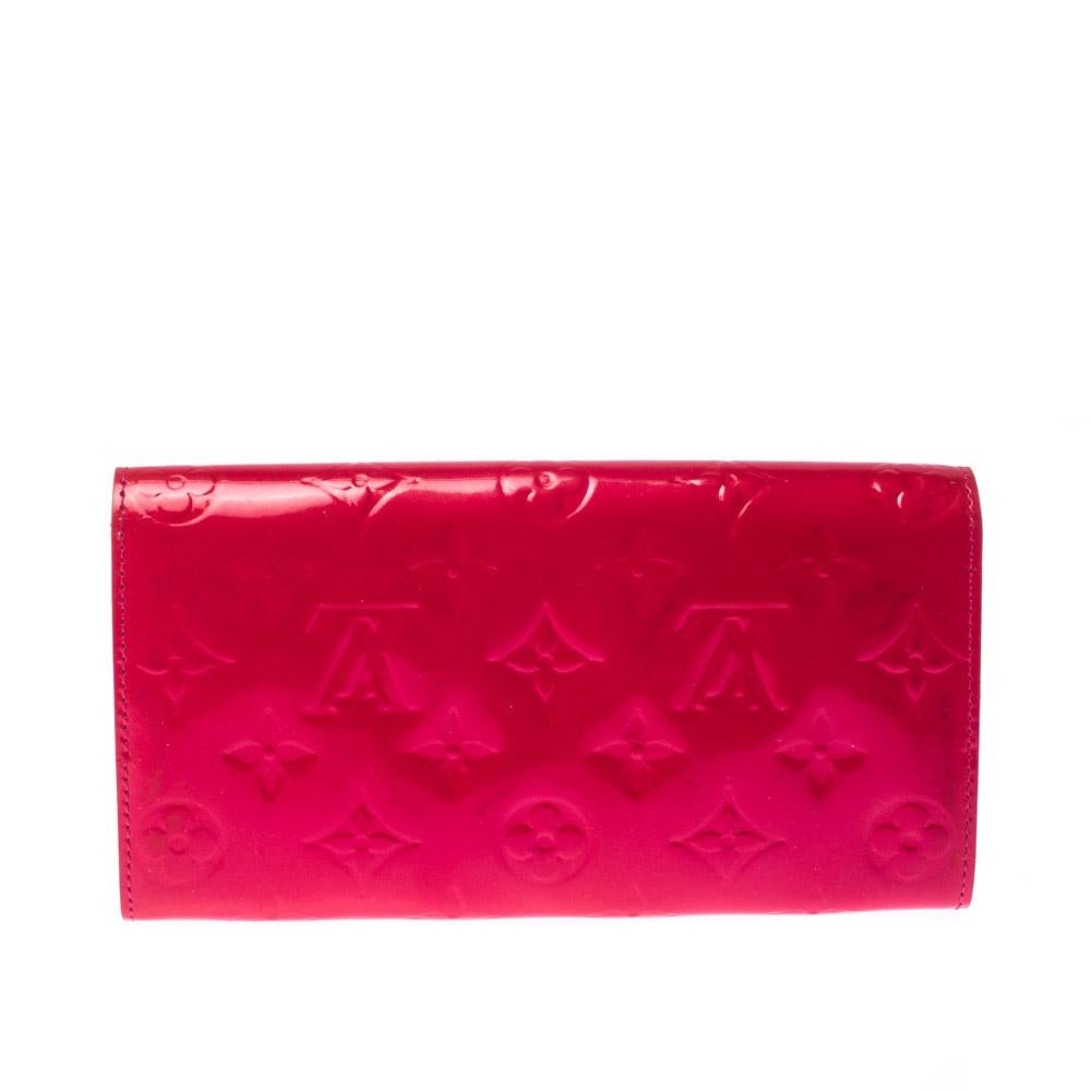One of the most famous wallets by Louis Vuitton is the Sarah. This one here comes made from monogram patent leather and the button on the flap opens to an interior with multiple card slots and a zip pocket. Perfect in size, this wallet can easily