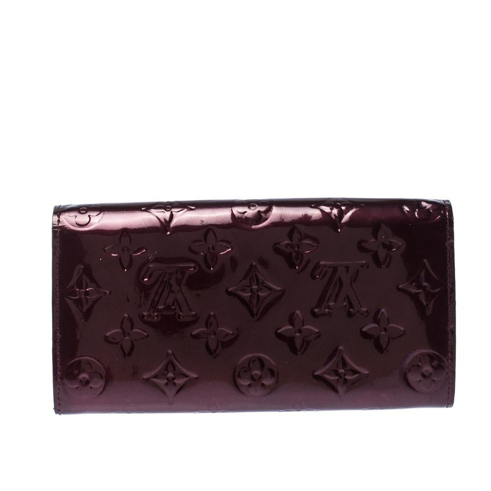 One of the most famous wallets by Louis Vuitton is Sarah. This one here comes made from Monogram Vernis and the button on the flap opens to an interior with multiple card slots and a zip pocket. Perfect in size, this wallet can easily fit inside