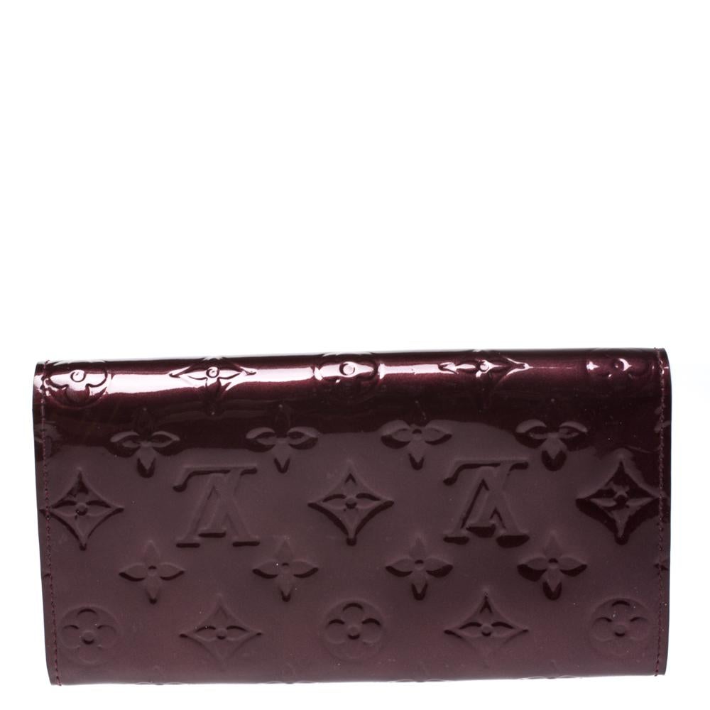 One of the most famous wallets by Louis Vuitton is Sarah. This one here comes made from Monogram Vernis and the button on the flap opens to an interior with multiple card slots and a zip pocket. Perfect in size, this wallet can easily fit inside