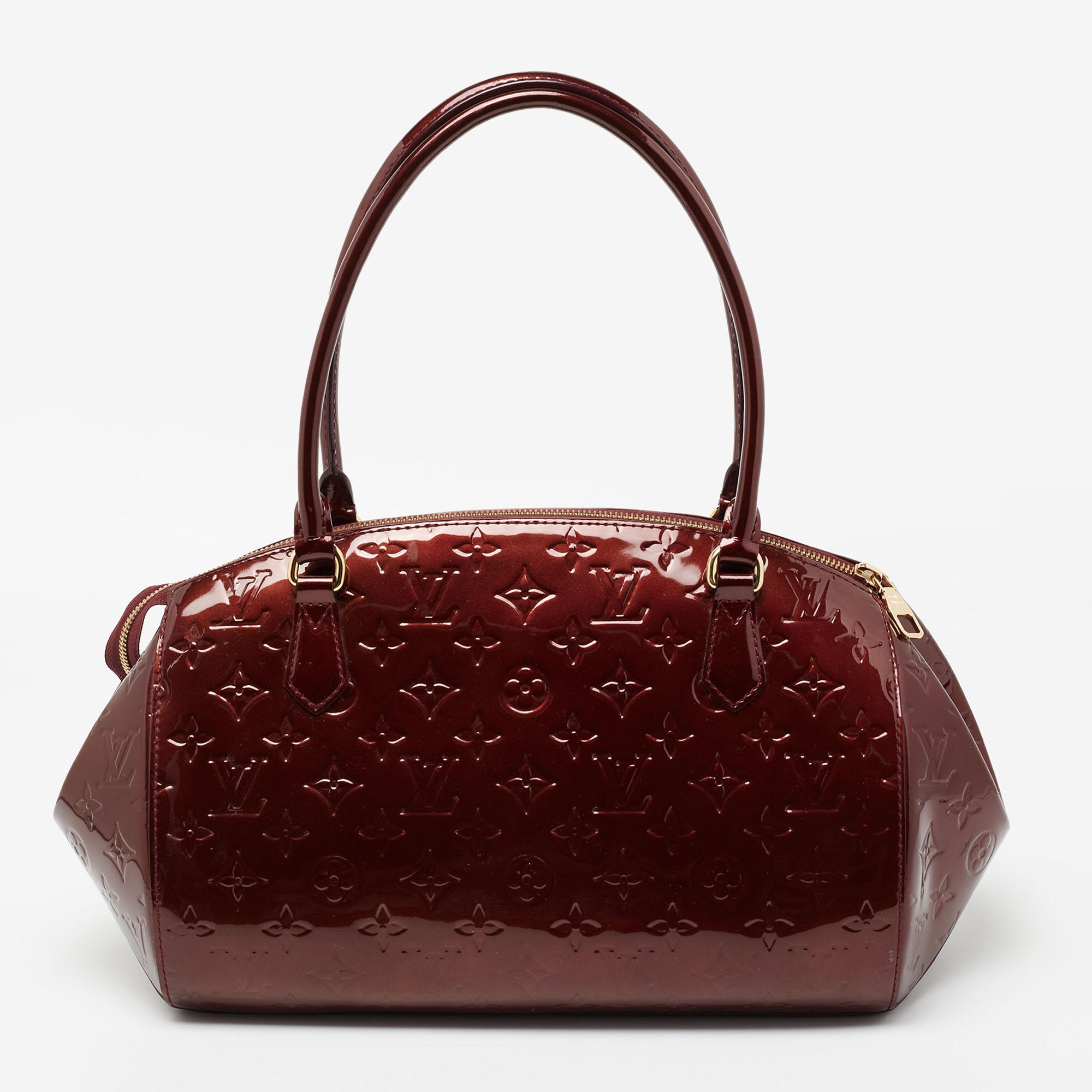 The Vernis line from Louis Vuitton was originally released in 1998. Today, these designs continue to inspire. Made with Monogram Vernis, this Sherwood is matched with gold-tone hardware. Top handles make it comfortable to carry. This bag is designed