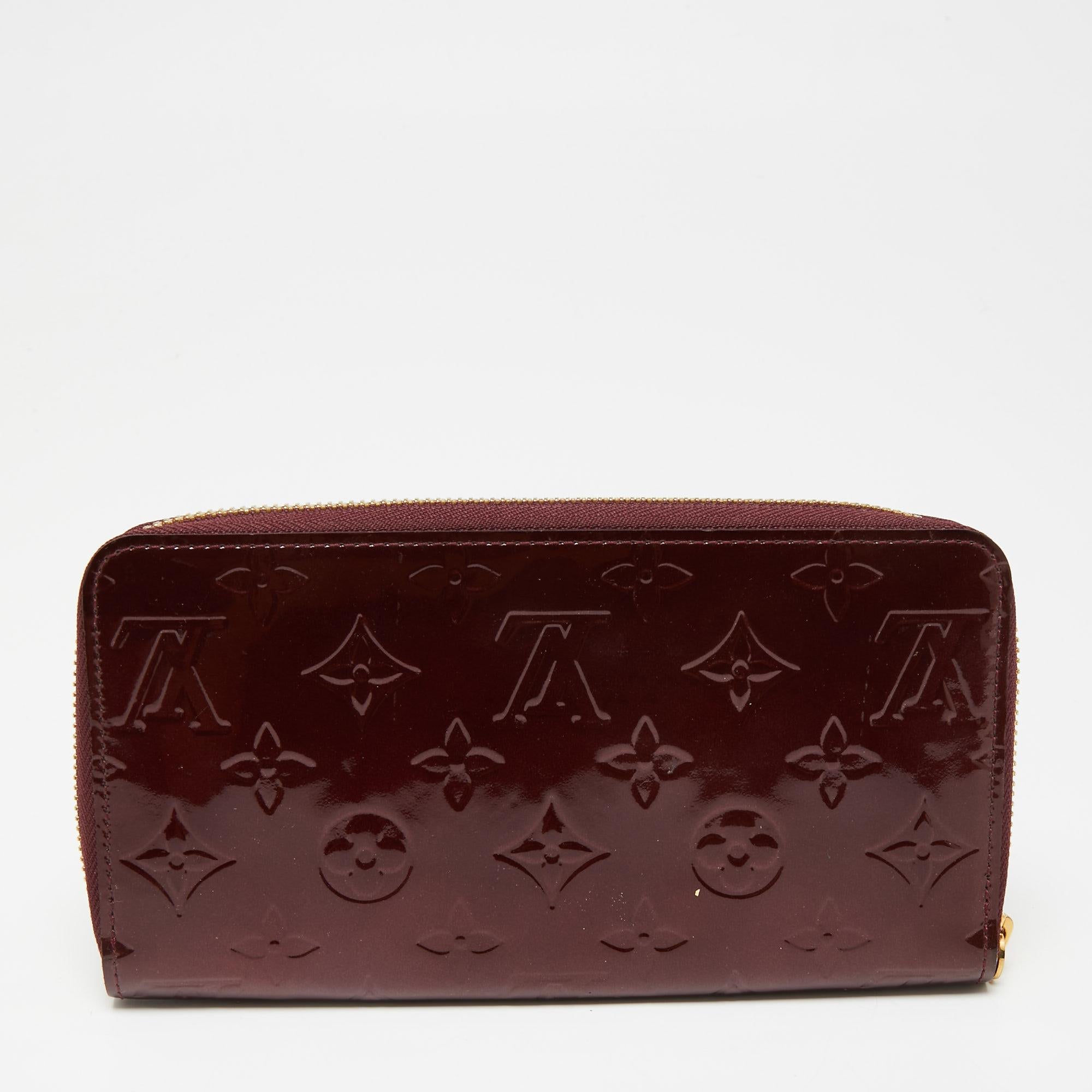 This Louis Vuitton Zippy wallet is conveniently designed for everyday use. Crafted from the signature monogram Vernis patent leather, it is paired with a zip-around closure and gold-tone hardware. The compartmentalized interior of the wallet will